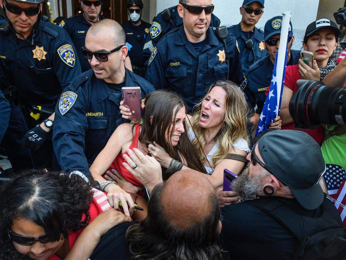 Protester Heidi Munoz Gleisner, left, was removed from a demonstration against Gov. Gavin’s Newsom’s stay-at-home order by California Highway Patrol officers after they ordered a crowd of people to leave the Capitol grounds Friday, May 1, 2020, in Sacramento.