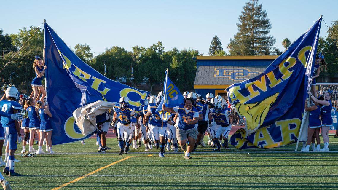 The Del Campo Cougars football team runs onto the field before the game against the Bella Vista Broncos on Friday, Sept. 2, 2022, at Del Campo High School in Fair Oaks.