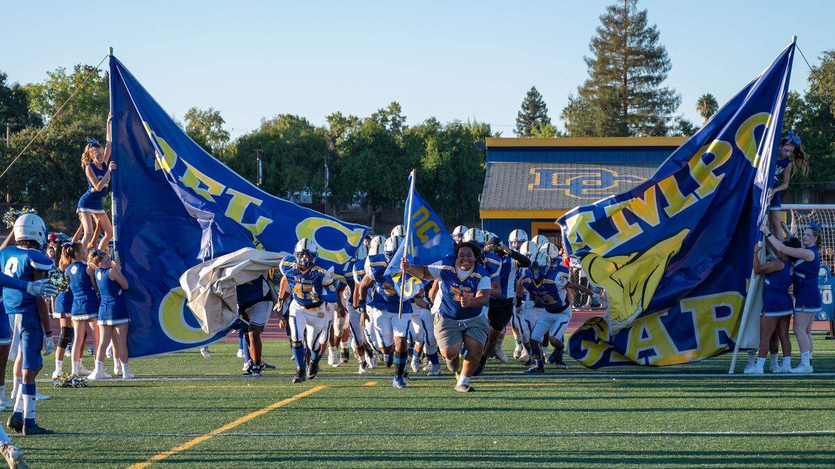 The Del Campo Cougars football team runs onto the field before the game against the Bella Vista Broncos on Friday, Sept. 2, 2022, at Del Campo High School in Fair Oaks.