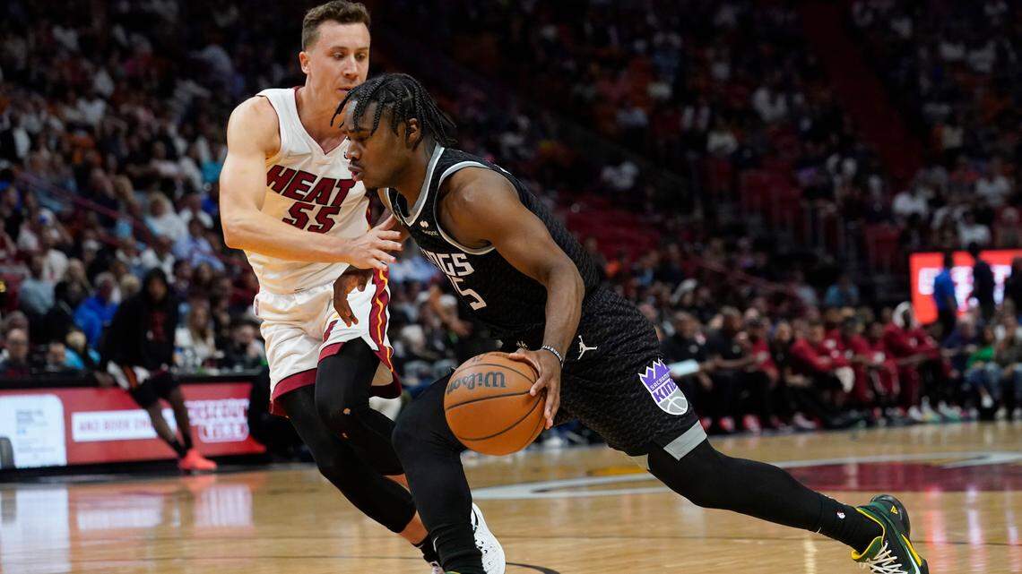 Sacramento Kings guard Davion Mitchell, right, dribbles around Miami Heat guard Duncan Robinson, left, during the first half of an NBA basketball game, Monday, March 28, 2022, in Miami. (AP Photo/Marta Lavandier)