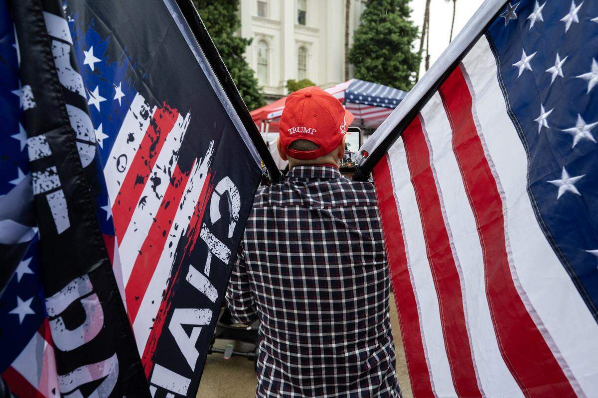 A man holds an American flag and a flag honoring slain conservative activist Charlie Kirk and an American flag during a memorial event marking his birthday at the state Capitol in Sacramento on Tuesday.