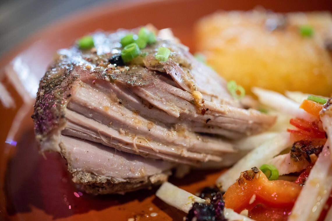 An order of the pernil — an entree served with yuca cake, salsa mocha, jicama and a sweet pepper slaw — makes its way to a diner at Bodega Kitchen & Cocktails in 2022. The Greenhaven restaurant closed Saturday, Nov. 15, due to rising costs and declining sales.