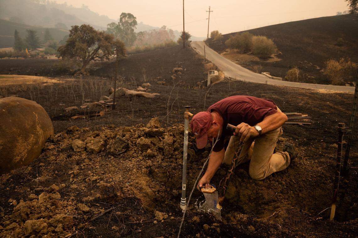 Kurt Balasek fixes plumbing on his property for water from a community well on Quail Canyon Road on Thursday, Aug. 20, 2020, as he assess damage from the LNU Lightning Complex fires in Solano County. Balasek’s wife and father, who went through the fire in Paradise, evacuated earlier, while he stayed to try and defend the house, which ended up standing amid heavy damage in the area.
