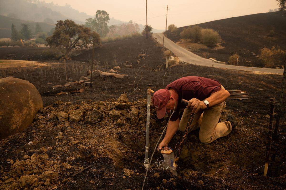 Kurt Balasek fixes plumbing on his property for water from a community well on Quail Canyon Road on Thursday, Aug. 20, 2020, as he assess damage from the LNU Lightning Complex fires in Solano County. Balasek’s wife and father, who went through the fire in Paradise, evacuated earlier, while he stayed to try and defend the house, which ended up standing amid heavy damage in the area.
