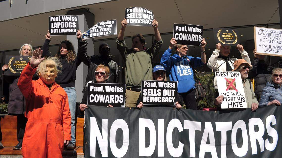 A demonstrator wearing a Donald Trump mask and an orange jumpsuit stands next to other demonstrators outside the office of the law firm Paul, Weiss, Rifkind, Garrison & Wharton last month to protest the firm's deal with Trump to avoid being targeting with an executive order. The deal includes the firm providing $40 million worth of free legal services for the Trump administration and the firm removing its diversity, equity and inclusion policies. 