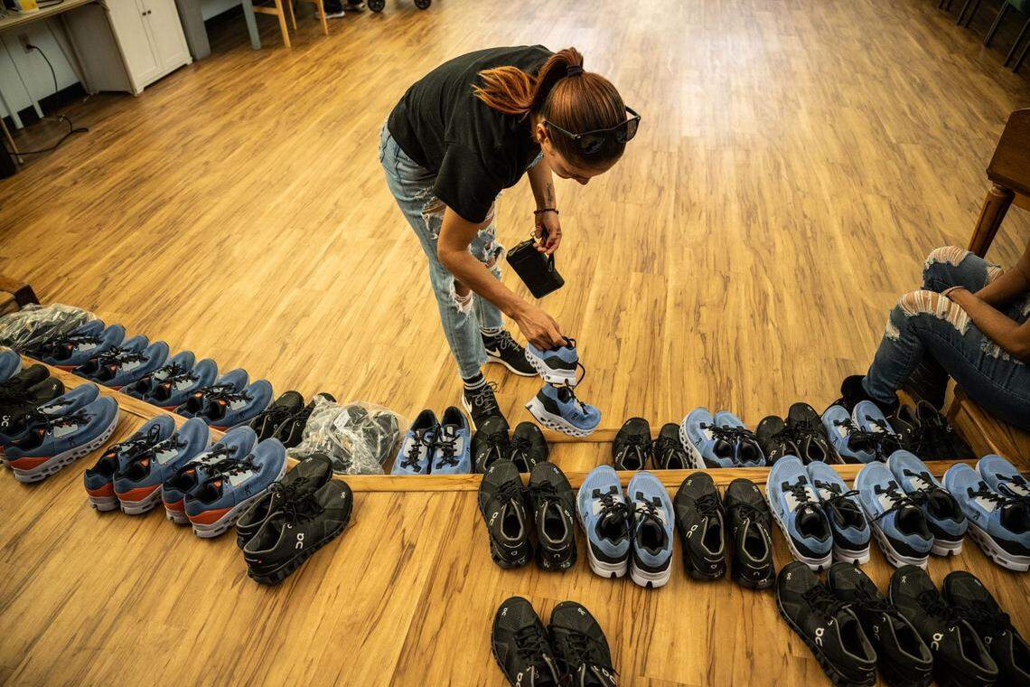 A migrant mother of three looks at running shoes Friday that were donated to the group in Sacramento after they were transported to the city from El Paso, Texas, on two plane flights by a Florida contractor.