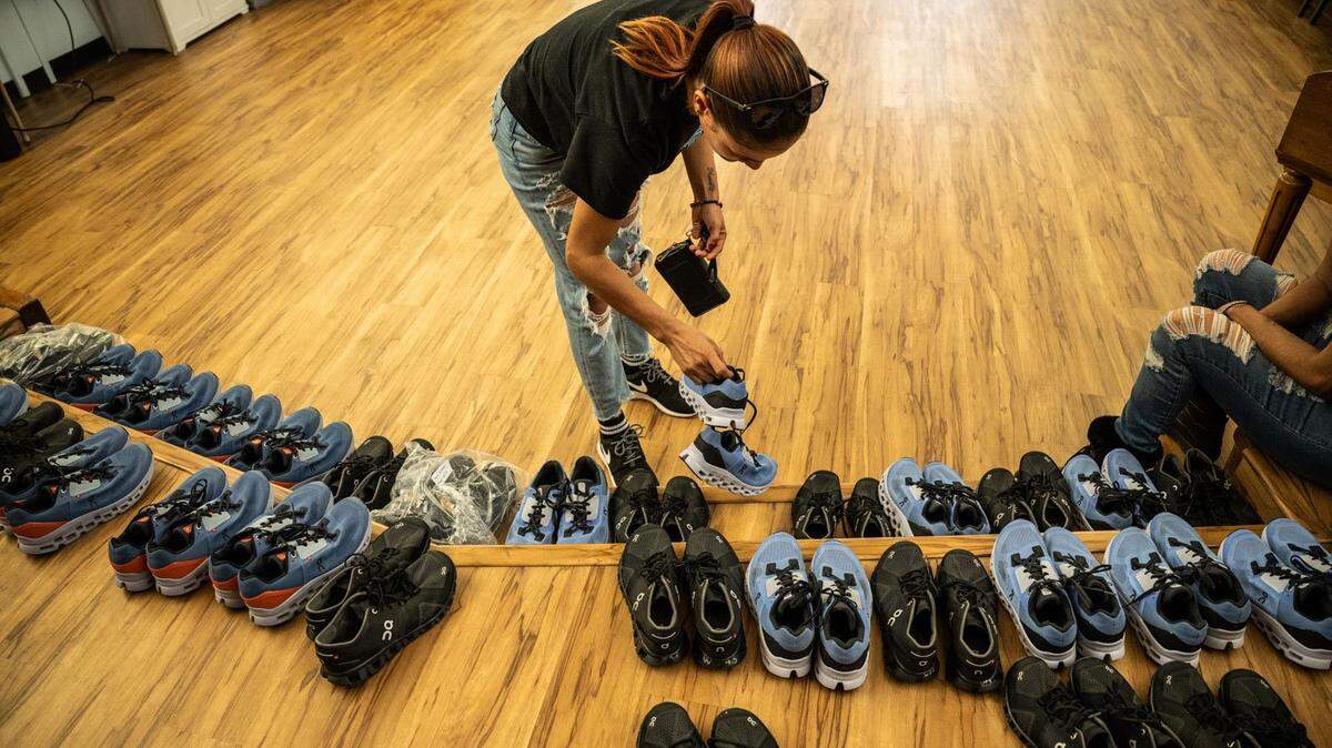 Una madre migrante con tres hijos mira, el viernes 16 de junio de 2023, las zapatillas deportivas que fueron donadas al grupo en Sacramento, después de que fueran transportados a la ciudad desde El Paso, Texas, en dos vuelos por un contratista de Florida.