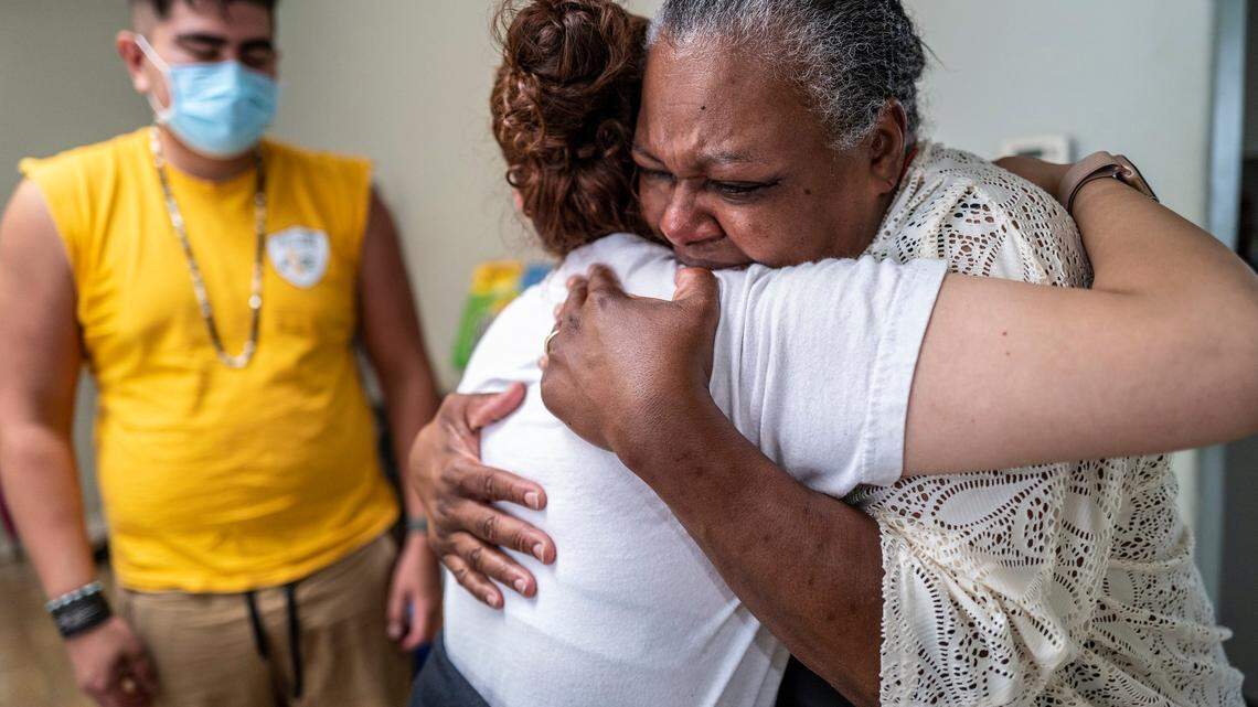 Mónica Madrid, organizadora comunitaria de Alliance of Californians for Community Empowerment, consuela a Lenora Jackson, de 55 años, en South Oak Park a principios de este mes, mientras Luis Fernando Anguiano, también de ACCE, se encuentra a la izquierda. A Jackson le preocupa quedarse sin hogar si no puede permanecer en su casa de renta.