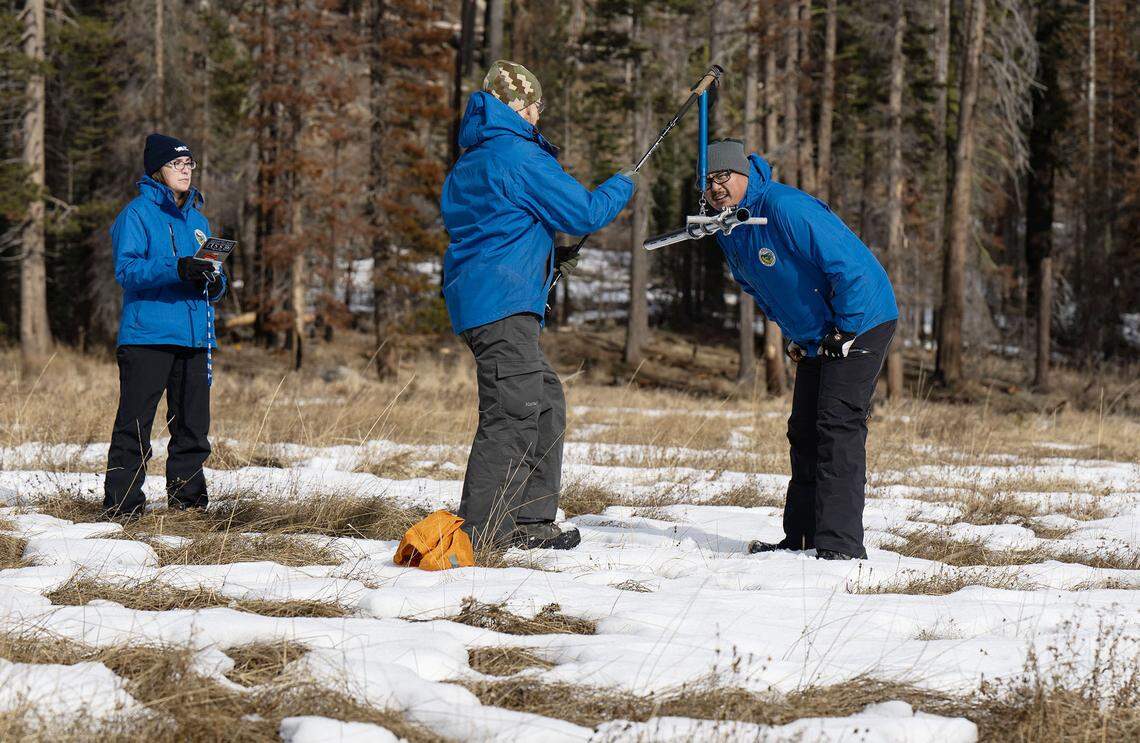 Sean de Guzman, right, snow survey manager at the Department of Water Resources, and engineer Anthony Burdock, center, measure the water content during the first snow survey of the season at Phillips Station in El Dorado County on Tuesday, Jan. 2, 2024.