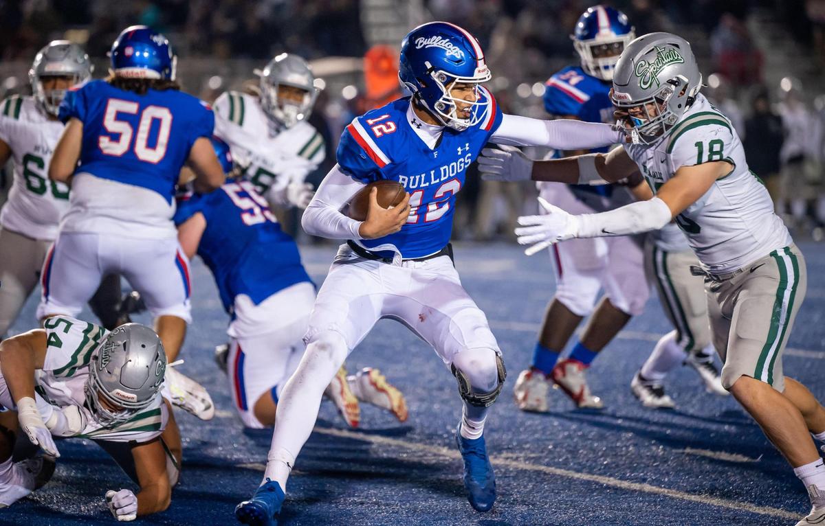 Folsom Bulldogs quarterback Austin Mack (12) tries to fend off De La Salle Spartan outside linebacker Andrew Cunningham (18) during the CIF Northern California Division I-A Regional Championship game in December.