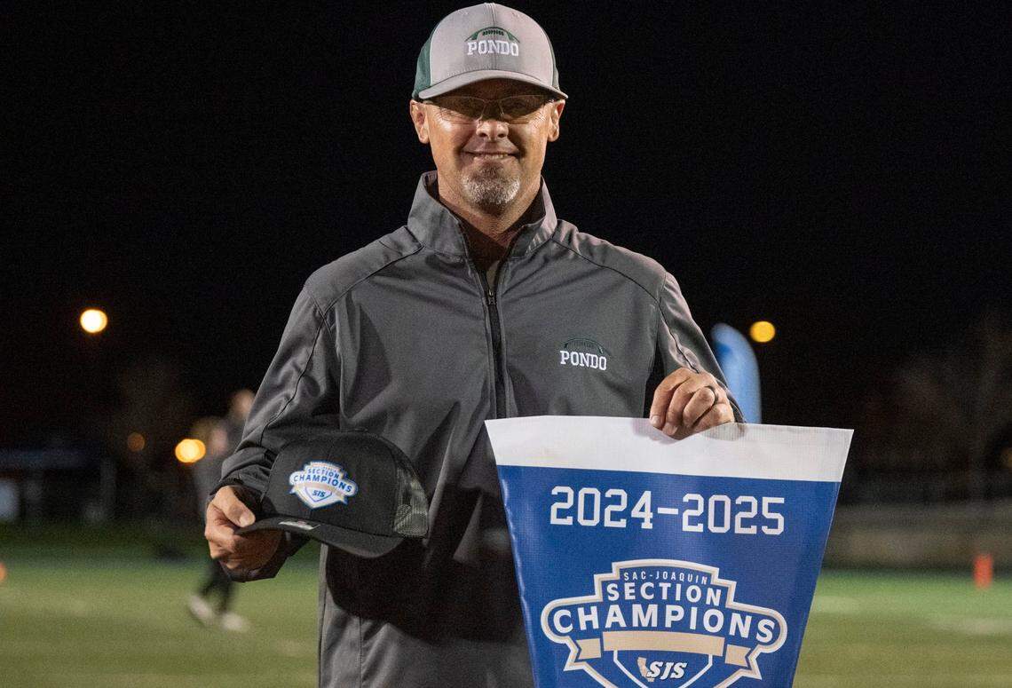 Ponderosa coach Tyson Escobar holds up the Sac-Joaquin Section championship banner after his team won the Division II championship girls flag football game in November. The Bruins were undefeated in their first season playing the sport.