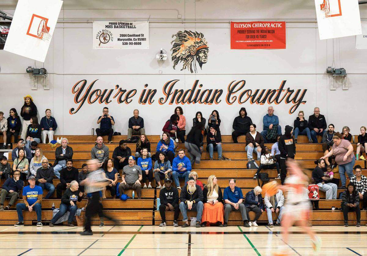 “You’re in Indian Country” reads a mural on the wall in the Marysville High School gym as a girls basketball player moves the ball down the court in a 2025 playoff game.