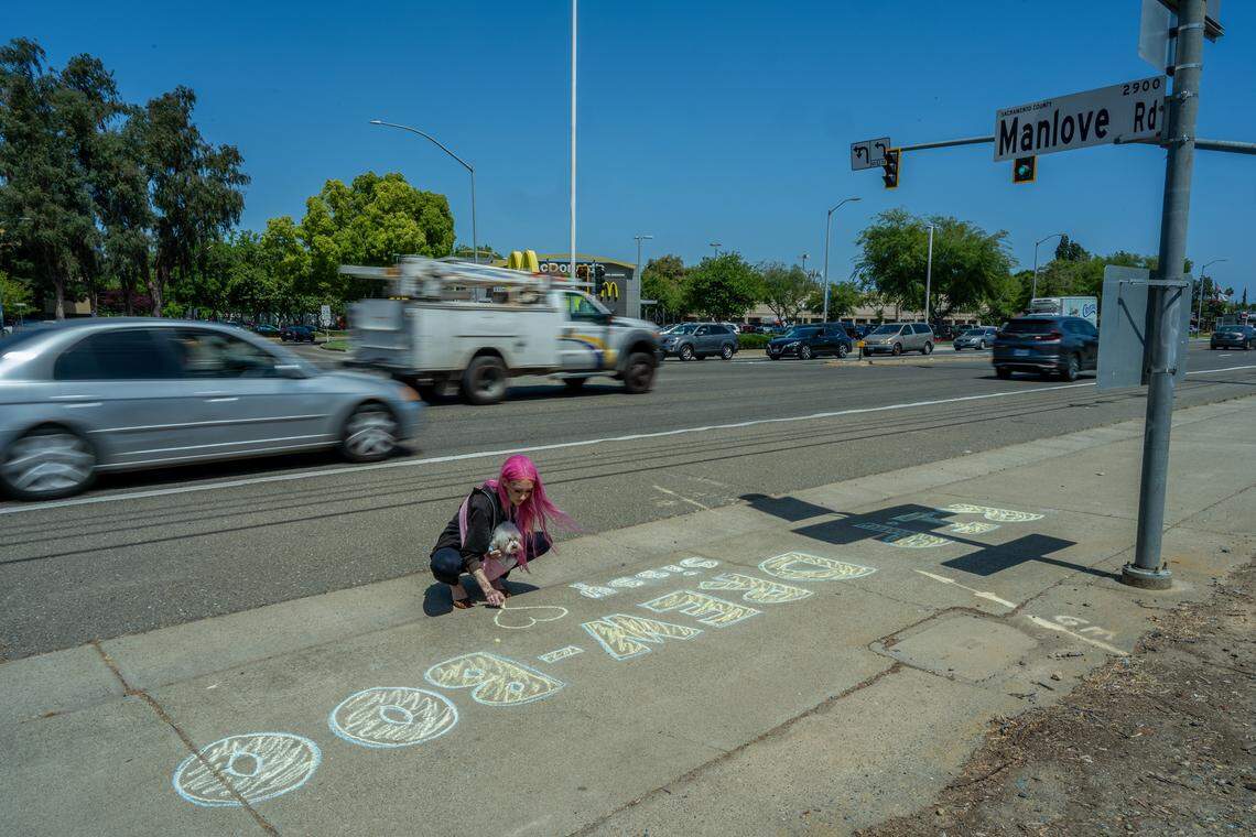Erika Pringle holds her dog, Boo, while drawing a message for her brother, Andrew Pringle, whom she nicknamed “Drew-Boo,” near the site where he was killed on April 23 — the two-year anniversary of his death. After his death, Erika said a medium told her she would be given an animal — later, her boss gave her Boo, who was born with a club foot, like her brother.