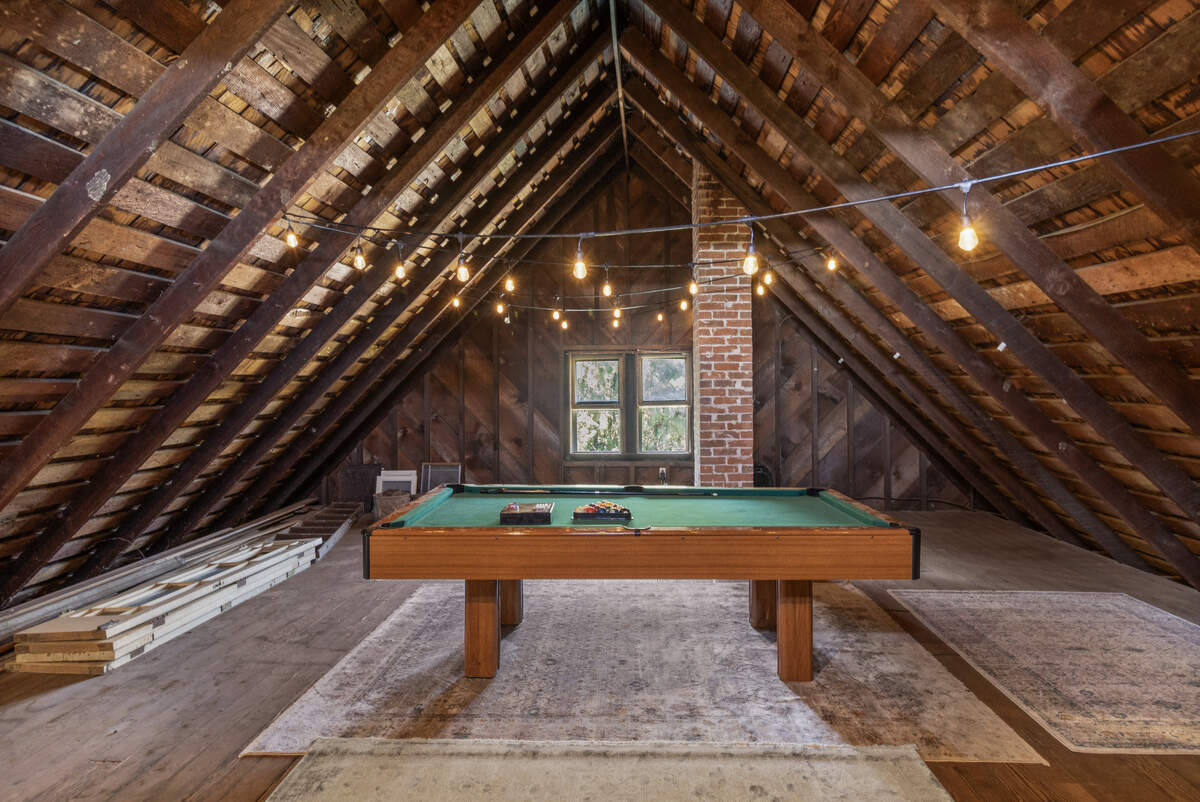The attic, once storage, now serves as a whimsical retreat with a children’s game room and a quieter nook. Exposed first-growth redwood framing and original cedar shingles are visible.