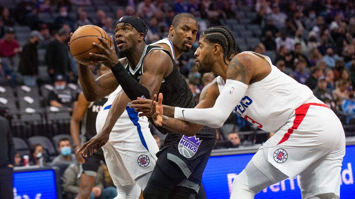 Sacramento Kings guard Terence Davis, left, drives to the basket past Los Angeles Clippers center Serge Ibaka and guard Paul George during the first quarter of an NBA basketball game in Sacramento, Calif., Saturday, Dec. 4, 2021. (AP Photo/Randall Benton)