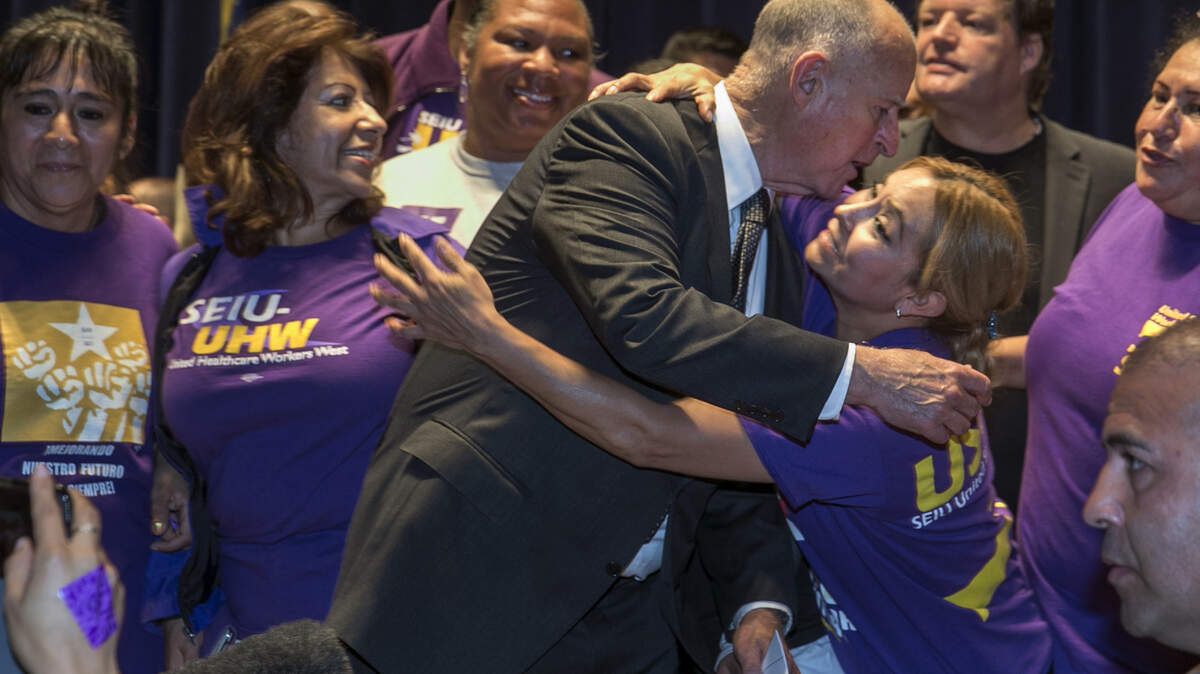 California Gov. Jerry Brown is surrounded by SEIU members after signing a bill raising the state’s minimum wage to $15 an hour by 2022 at a ceremony in Los Angeles in April 2016.