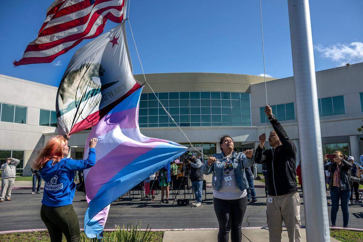 SCUSD Student Board Member Liam McGurk, center, helps raise the transgender flag outside the Serna Center in Sacramento on Monday3. The flag will be flown for the remainder of March in observance of Trans Day of Visibility on March 31.