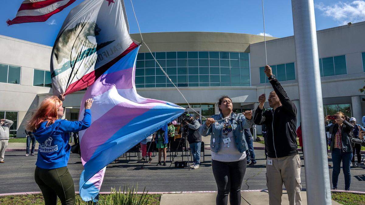 SCUSD Student Board Member Liam McGurk, center, helps raise the transgender flag outside the Serna Center in Sacramento on Monday, March 20, 2023. The event was the first annual Trans Day of Visibility flag raising. The flag will be flown for the remainder of March in observance of Trans Day of Visibility which is March 31.