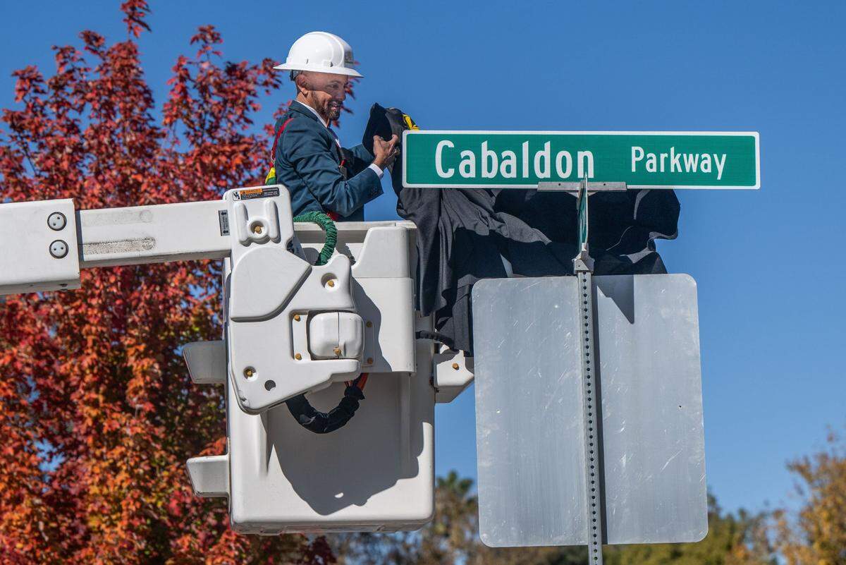 Christopher Cabaldon, the former mayor of West Sacramento, removes a cover from a street sign as the city renames the Tower Bridge Gateway in his honor on Wednesday.