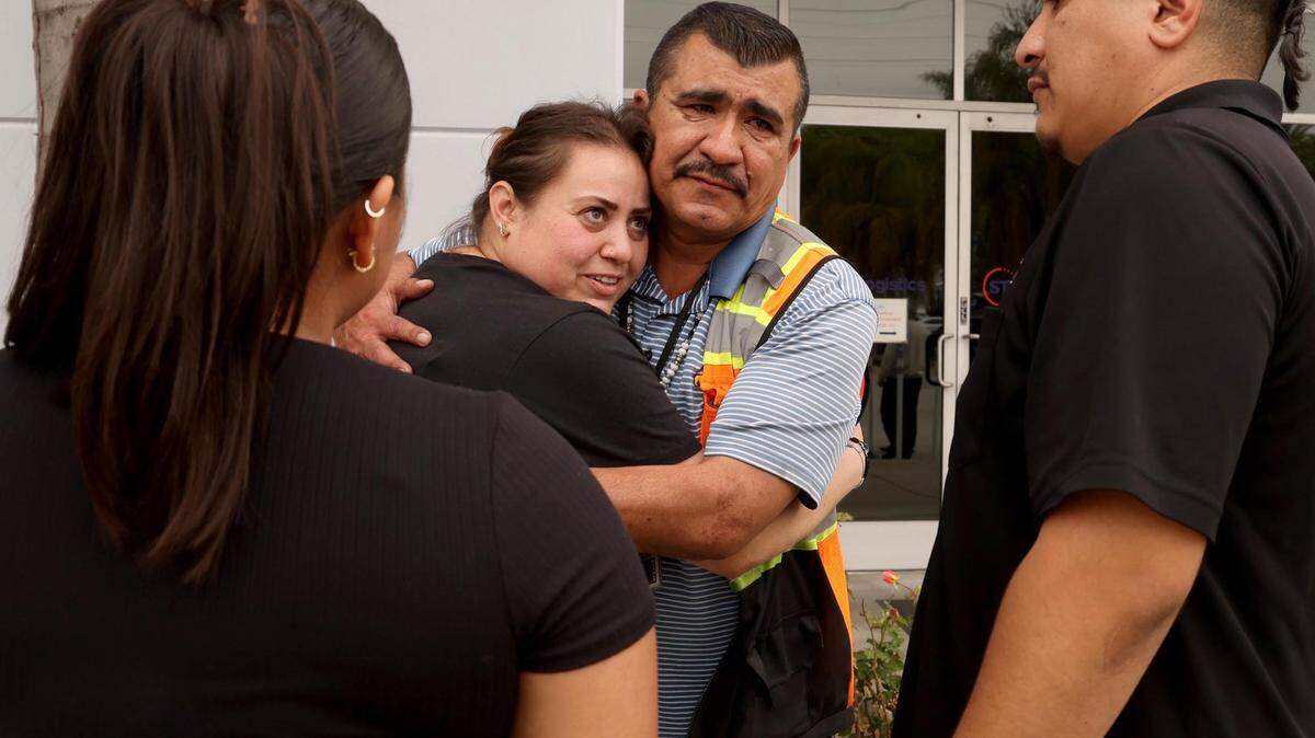 An emotional STG Logistics vendor Noel H., center, hugs a family member after an ICE raid at the facility in Compton, California, on June 12, 2025.