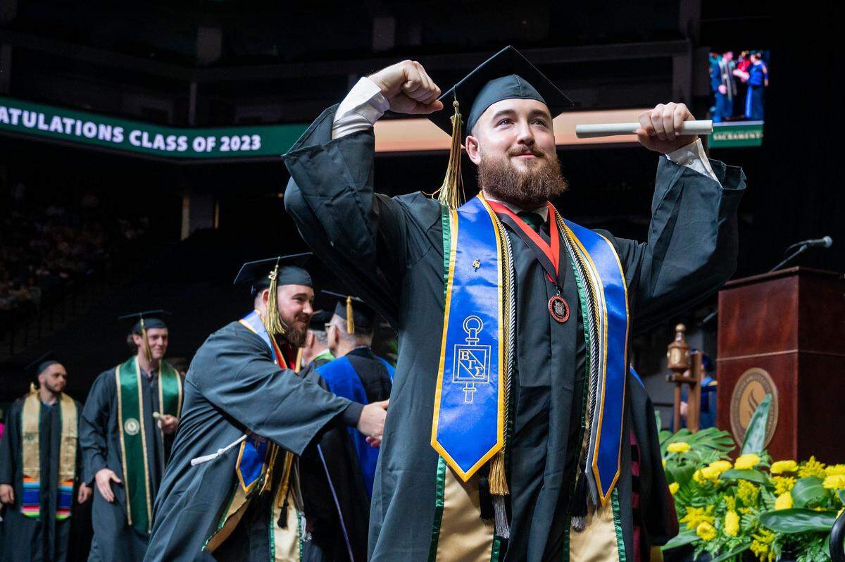 Jet Green flexes as he walks off the stage during the Sacramento State College of Business commencement on Friday.