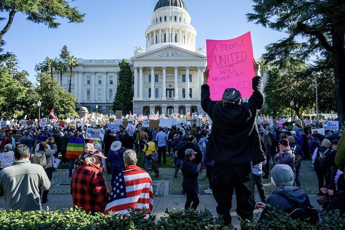 A demonstrator holds up a sign “A people united will never be divided” as she joins hundreds at a protest against President Donald Trump and his adviser Elon Musk at the California Capitol on Wednesday.