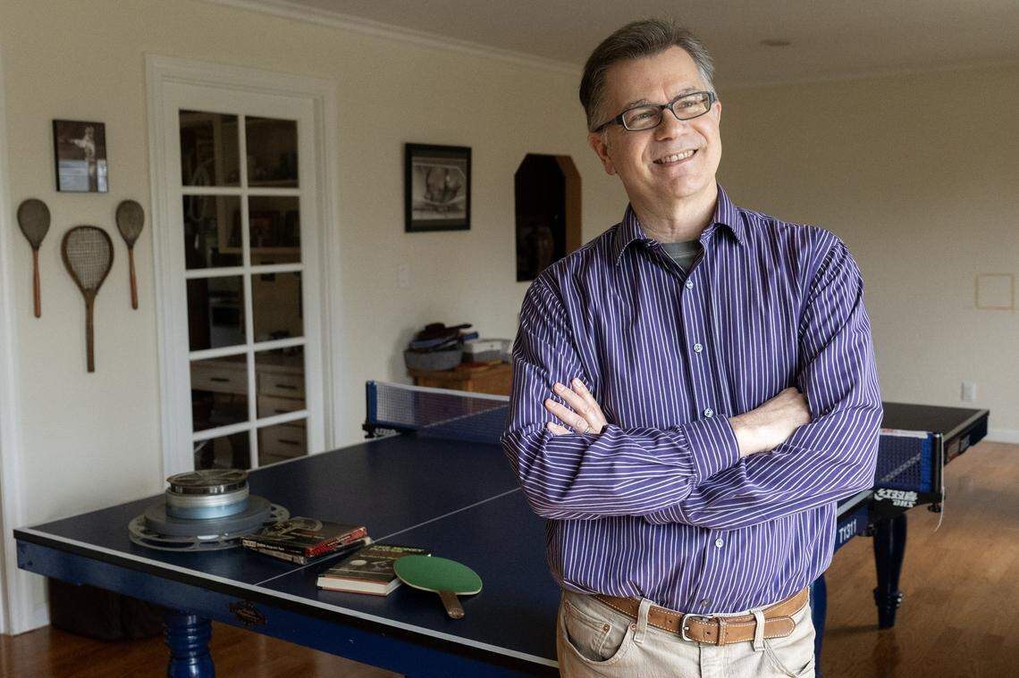Scott Gordon stands with his archive of table tennis star Marty Reisman, including 16mm film, audiotapes and photographs, at home in Carmichael earlier this month. Gordon served as a table tennis consultant for the upcoming film “Marty Supreme,” based on Reisman.