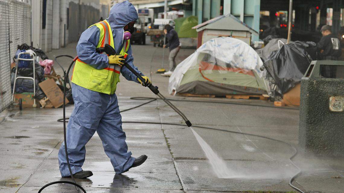 A San Francisco city worker uses a power washer to clean the sidewalk by a tent city in 2016. San Francisco plans to deploy a six-person poop patrol to clean up city streets and sidewalks after an avalanche of complaints about human waste.