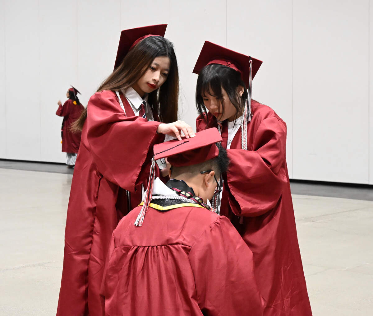 Jiawen Li, right, and Zhiying Huang, left, adjust a friend’s mortarboard at the Hiram Johnson High School graduation on Wednesday.