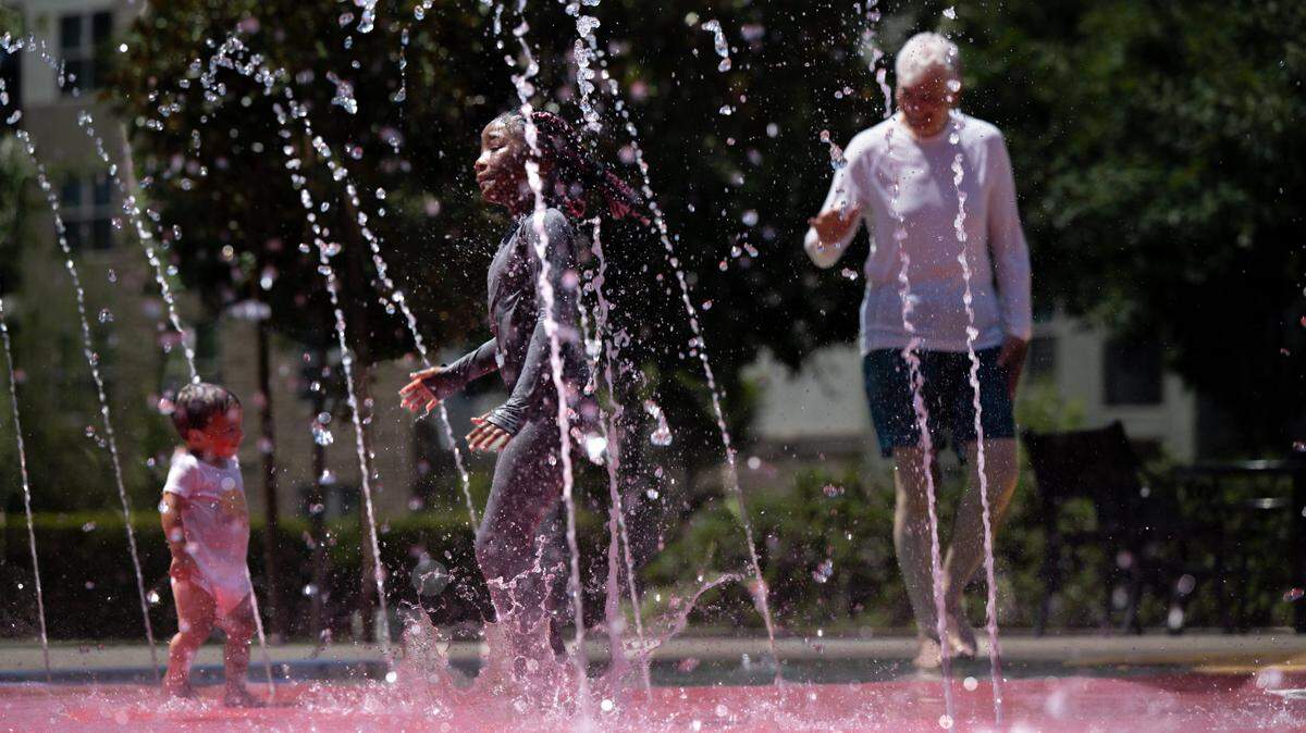 Rancho Cordova resident, Inari Track, 6, center, cools down with Londyn Winston, 18-months, and Hans Gregerson in the water fountain in Village Green Park on Thursday, July 11, 2024, in Rancho Cordova.