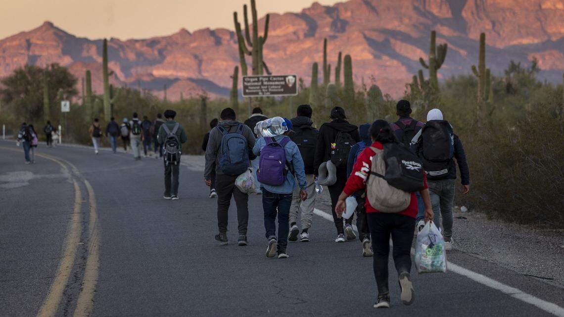 Inmigrantes caminan hacia Estados Unidos después de cruzar la frontera entre EEUU y México el 7 de diciembre de 2023, en Lukeville, Arizona. La oleada de inmigrantes que cruzan ilegalmente a través de las aberturas practicadas por contrabandistas en el muro fronterizo ha desbordado a las autoridades de inmigración de EEUU, obligándolas a cerrar varios puertos de entrada internacionales para que los agentes puedan ayudar a procesar a los recién llegados.