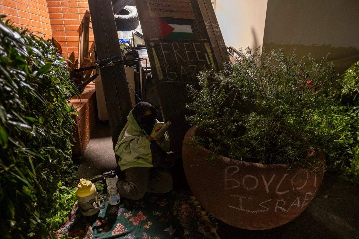 Cal Poly Humboldt student Laura Sanchez sits outside of barricaded Siemens Hall, where students and community members have locked themselves inside to call for a permanent ceasefire in Gaza, on Tuesday, April 23, 2024, in Arcata.