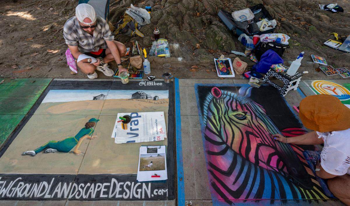 Artists Brent Warnken, left, and Cynthia Barrows work on their sidewalk art at Chalk it Up festival on Sunday at Fremont Park.