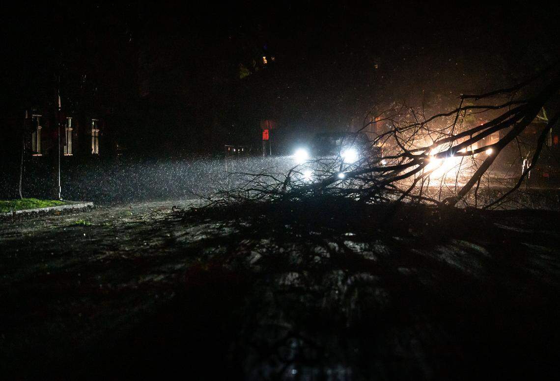 Vehicles maneuver around large fallen branches south on 15th Street, with traffic signals out and homes dark due to major power outages in the region, early Sunday, Jan. 8. 2023, in midtown Sacramento. Hundreds of thousands of homes and businesses lost power overnight Saturday due to another major storm hitting Northern California.