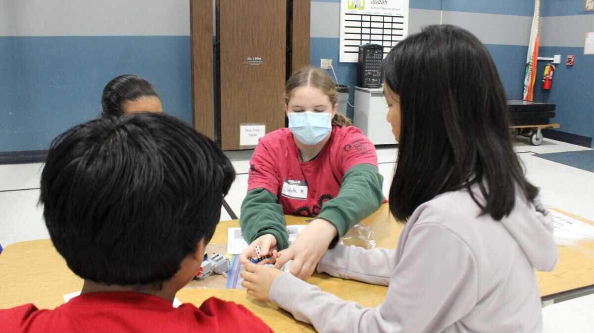 Eighth-grader Charlotte Miner, Metal Maniacs’ outreach curriculum lead, assists fourth- and fifth-graders with motorized Lego creations during a robotics workshop at Theodore Judah Elementary School on Tuesday, March 21, 2023. While Lego bricks are more accessible than metal in a classroom, Miner said the Lego parts that they build with have axles, space for motors and “this big, like, brick in the center where you can put the code onto.”