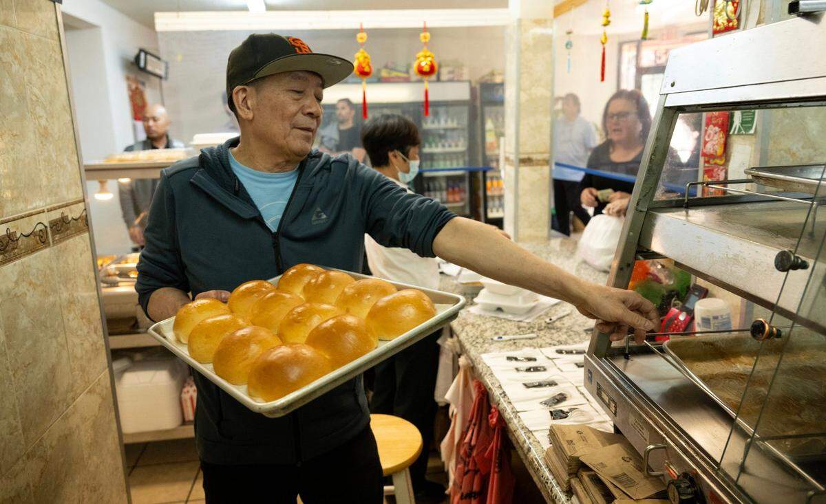 Owner Yao Li fills a warming bin with freshly baked cha sui bao, his most popular item at Lam Kwong Deli & Market, on March 20, 2024. They make more than 700 a day on weekdays and nearly 1,000 on Saturday.