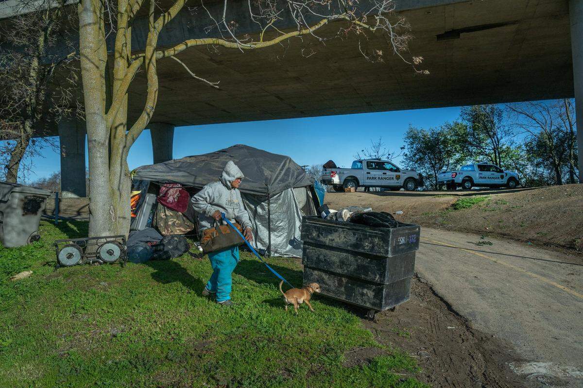 Victoria Reyes, 56, gets ready to push a cart with some of her belongings away from the Sacramento Northern Bike Trail in North Sacramento on Thursday. Park rangers had swept a nearby field the day before, and she lost all of her clothing but was able to keep her tarp shelter and four dogs. On Thursday, she was told she had to move again or she would get a citation for being on the bike trail.