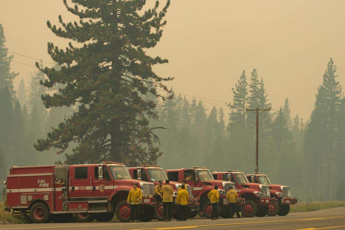 Cal Fire vehicles line up along Highway 50 in Strawberry on Sunday, as smoke from the Caldor Fire burning on both side of the route fills the air.