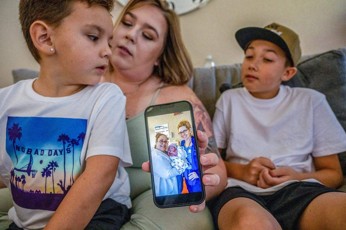 While sitting with his mom Kaitlyn Weiss and brother Liam Weiss, 11, at home in Modesto on Aug. 2, Beau Weiss, 6, left, glances down at an image of midwife Jessica Johnson holding him as a newborn with doula Lori Fenner. Beau was a VBAC birth and his brother Liam was a C-section delivery.