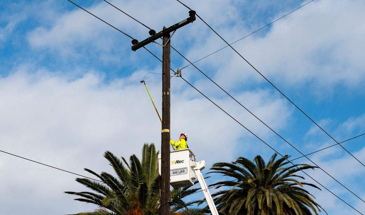 A SMUD worker attempts repairs to a power line on Riverside Boulevard in Land Park on Sunday, Jan. 8, 2022, after high winds downed trees and power lines across the street overnight.