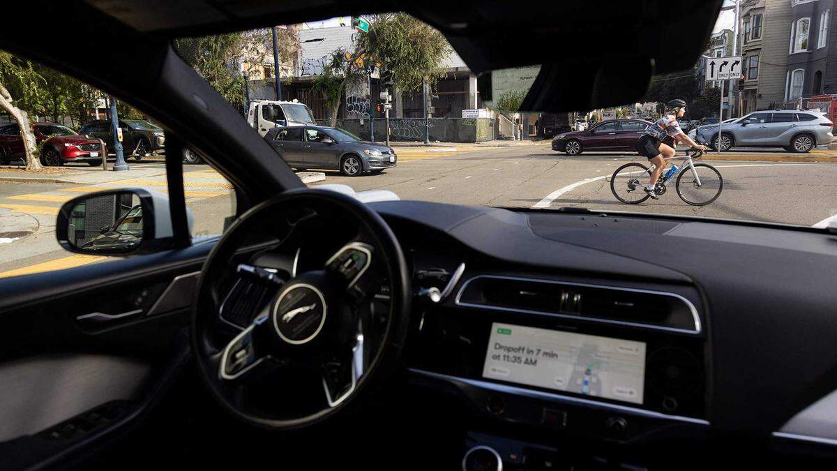 A cyclist rides past a Waymo autonomous vehicle on Oak Street in San Francisco in 2023. Testing in Sacramento will expose Waymo’s technology to frequent interactions with bikes and pedestrians, part of what one expert describes as the city’s multimodal transportation environment.