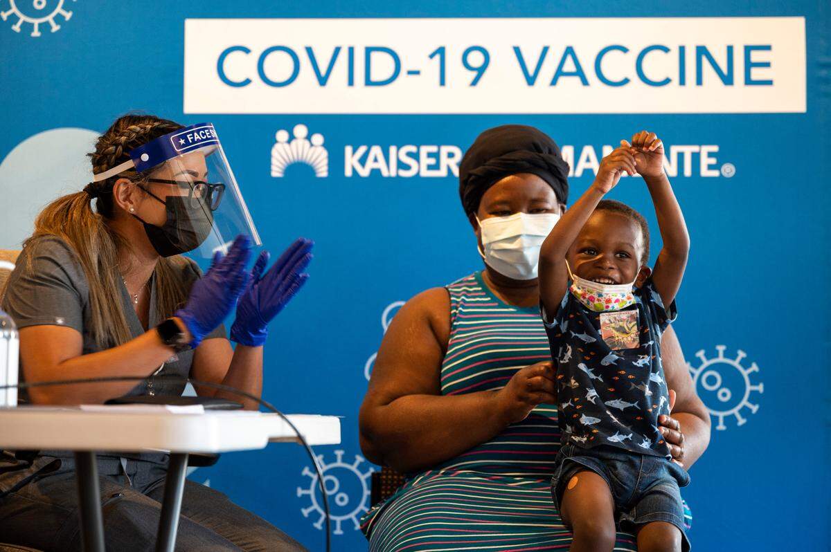 Bryan Yeboah, 3, celebrates after receiving the Moderna COVID-19 vaccination from nurse Joanna Marie Pamintuan earlier this year, while being held by mother Perpetual Yeboah at the Kaiser Permanente Bruceville Center Vaccination Clinic in Sacramento.. Under a new California law, doctors can be more easily punished by the Medical Board of California for deliberately spreading false information about COVID-19, vaccines and treatment.