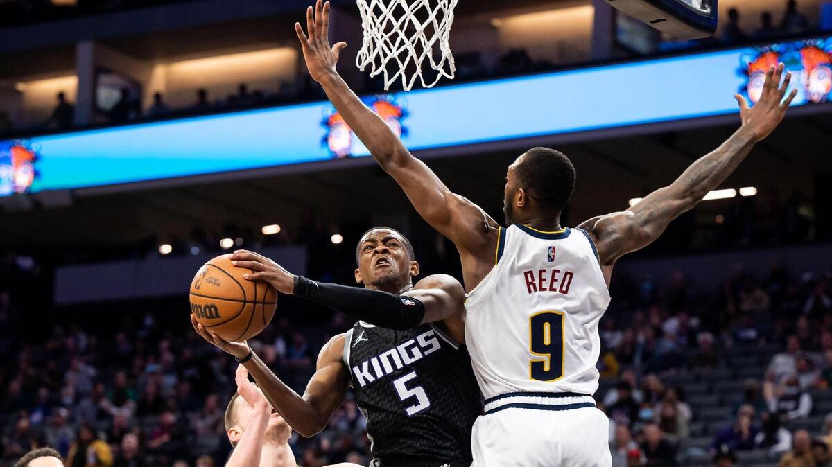 Sacramento Kings guard De’Aaron Fox (5) tries to pass thew ball out from under the basket as Denver Nuggets guard Davon Reed (9) during the second period at the NBA basketball game Wednesday, March 9, 2022, at Golden 1 Center in Sacramento.