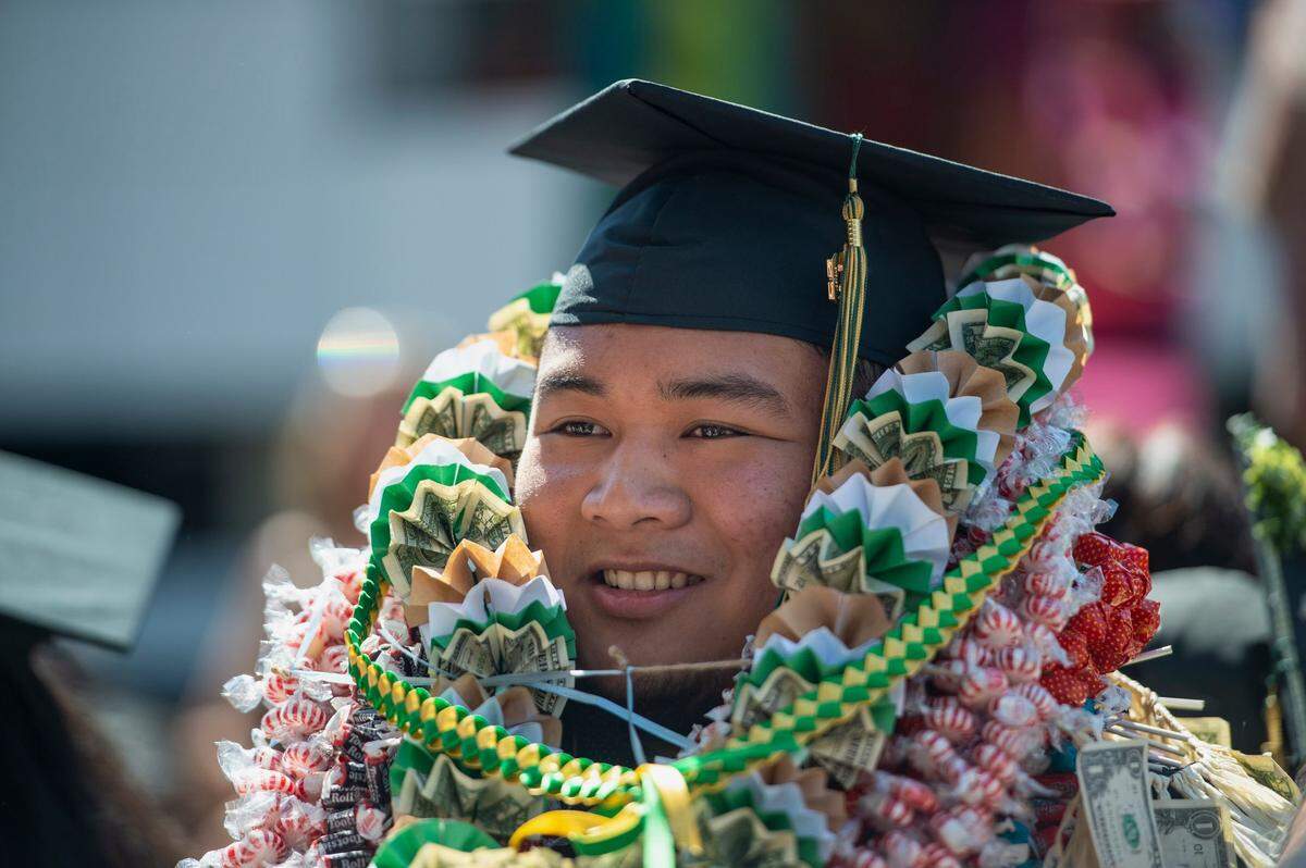 Neil Laquian takes photos with family after the Sacramento State College of Business commencement on Friday.