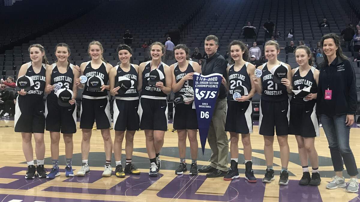 Forest Lake Christian players pose with the championship banner after winning the Sac Joaquin Section Division VI title Thursday at Golden 1 Center.