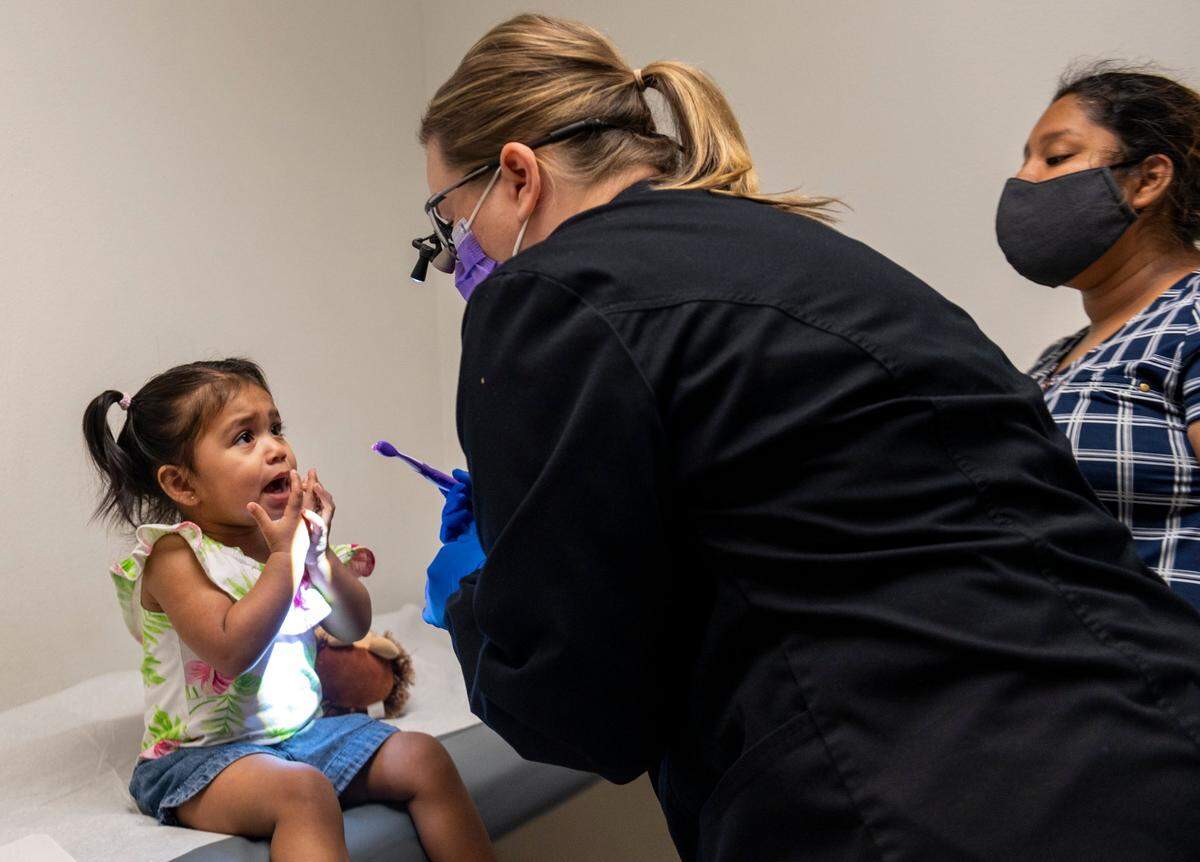 Angelic Mendoza Garcia, 18 months, receives a checkup from dental hygienist Jennifer Bidwell, center, while her mother, Maria Espinoza, observes as a part of the Every Smile Counts program at Walton Pediatrics and Medical Associates on Thursday, July 9, 2020. Every Smile Counts is a test program that places hygienists in schools – currently closed because of coronavirus concerns – and pediatricians’ offices to make it easier for Medi-Cal patients to receive dental education and services.