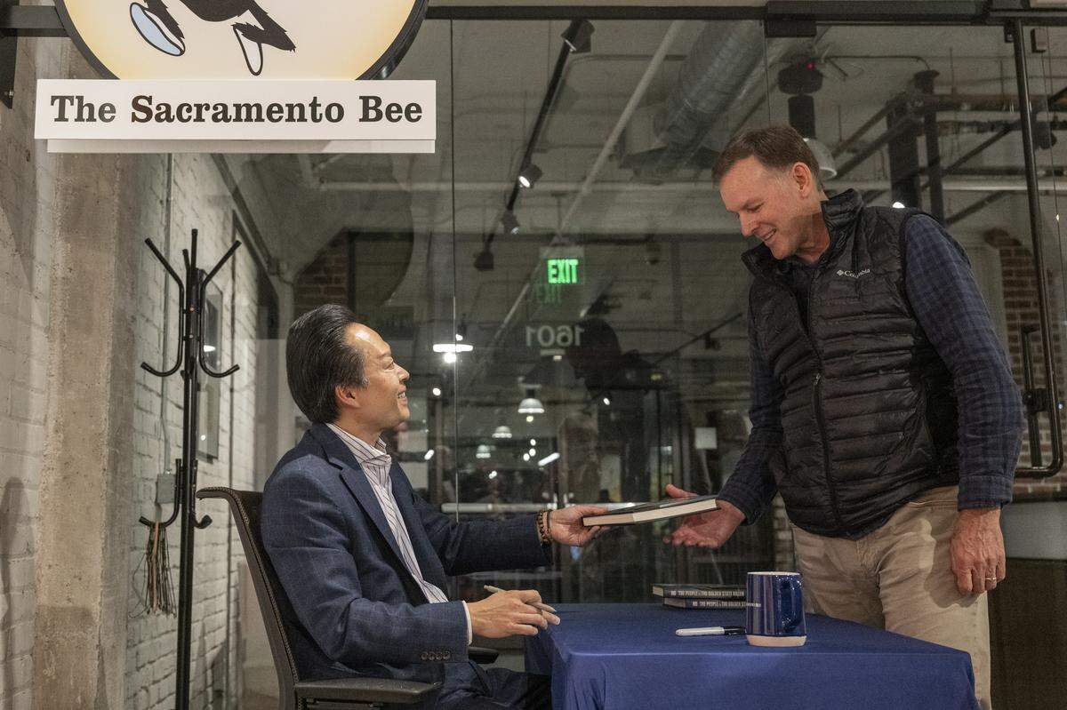 Sacramento County District Attorney Thien Ho, left, signs copies of his book “The People vs. the Golden State Killer” after a live Q&A at The Sacramento Bee’s office in Sacramento on Tuesday, Dec. 9, 2025.