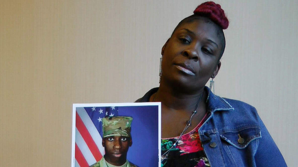 FILE - In this Nov. 27, 2018, file frame from video, April Pipkins holds a photograph of her deceased son, Emantic “EJ” Bradford Jr., during an interview in Birmingham, Ala. Bradford, who was licensed to carry a gun, was killed Thanksgiving night by an officer responding to a report of gunfire at a shopping mall in Hoover, Ala. The recent shootings of Bradford Jr. and Jemel Roberson amplified long-held worries that bad things can happen when a black man is seen with a gun. (AP Photo/Jay Reeves, File)