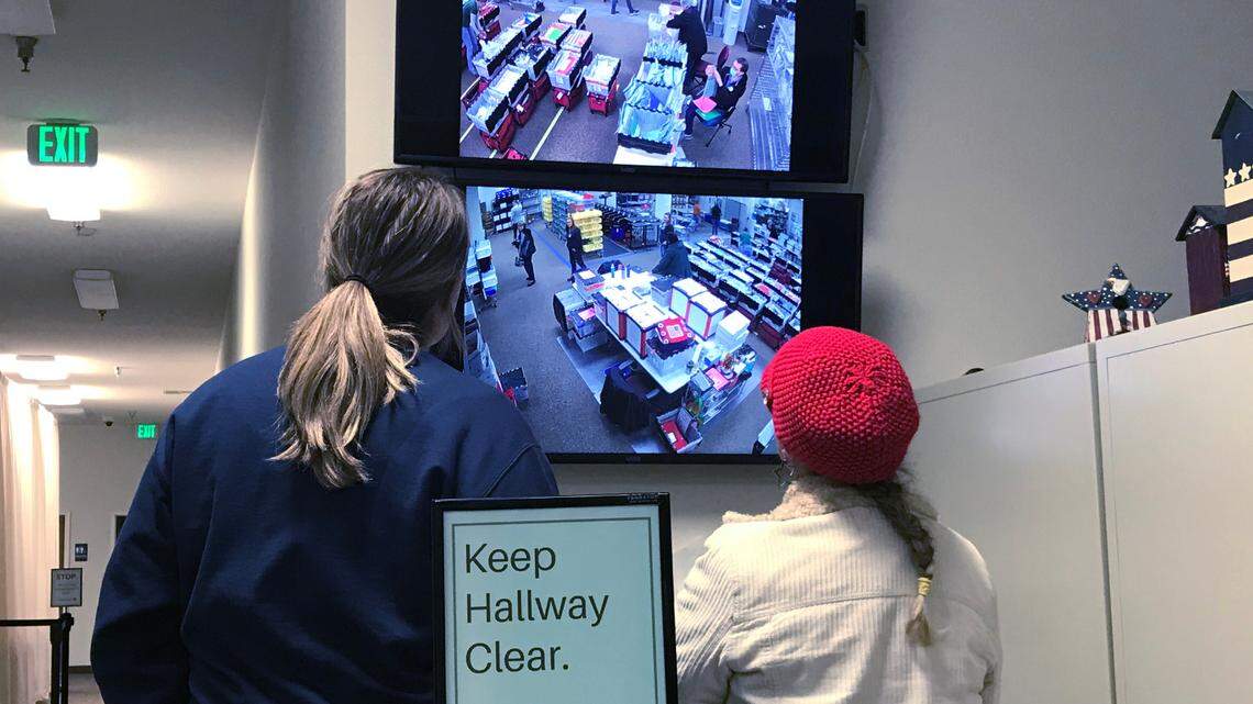 A Shasta County election worker, left, and an observer, watch workers on television monitors prepare the office before stopping work on election night, Tuesday, Nov. 8, 2022.