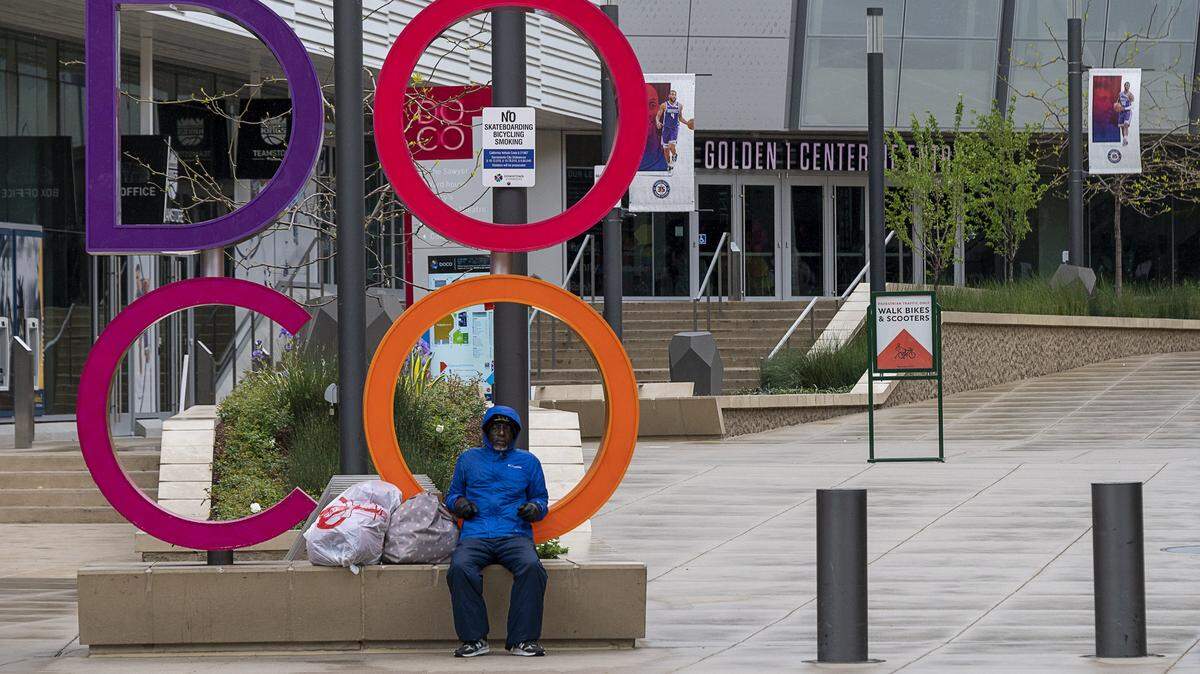A lone person sits on the sign at the entrance to the DoCo nearly empty plaza during the coronavirus outbreak on Tuesday, March 24, 2020 in Sacramento.